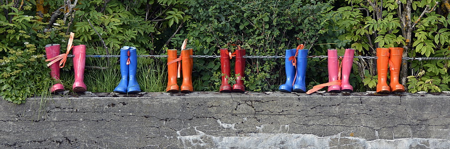 seven pairs of assorted-color rain boots on gray concrete wall