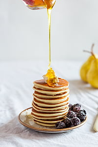 honey drizzled on stack of pancakes served on ceramic plate
