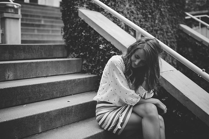 grayscale photo of woman sitting on stairs