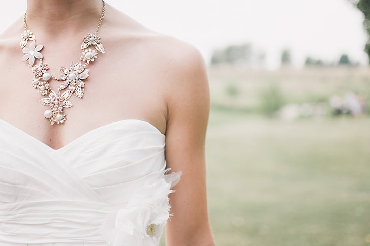 woman wears white sweetheart wedding dress on open field during daytime