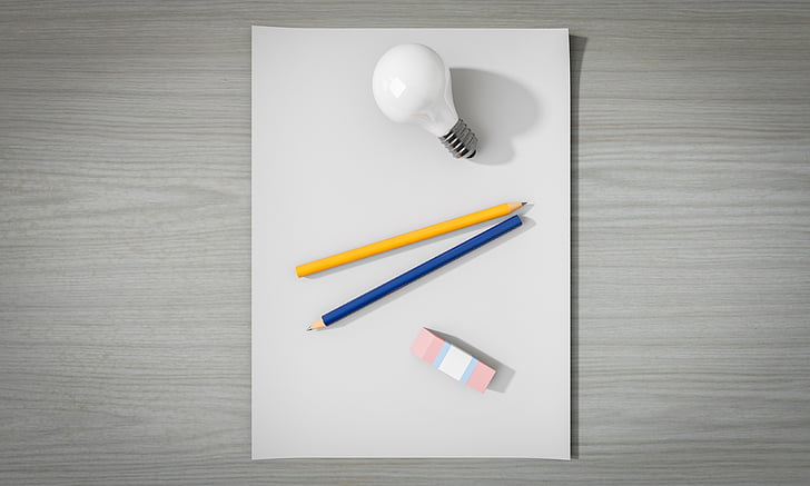 two yellow and blue pencils between LED bulb and eraser on white surface