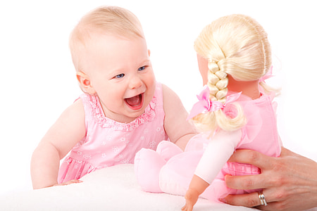 baby wearing pink dress near doll in pink dress