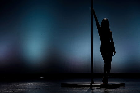 silhouette of woman standing near pole