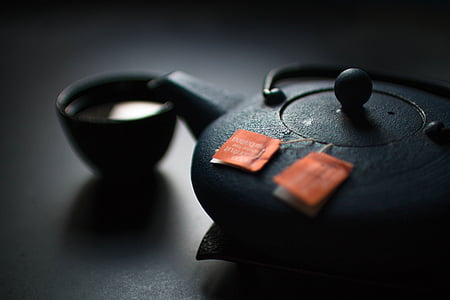 black ceramic teapot and teacup on black surface