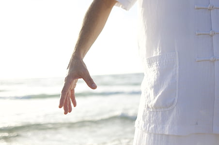 person wearing white shirt standing near seashore