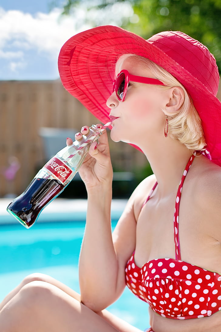 woman wearing red sunhat and bikini drinking Coca-Cola