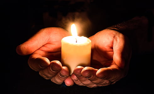 person holding pillar of candle with two hands