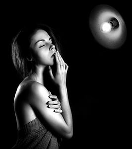 grayscale photo of woman in front of light bulb