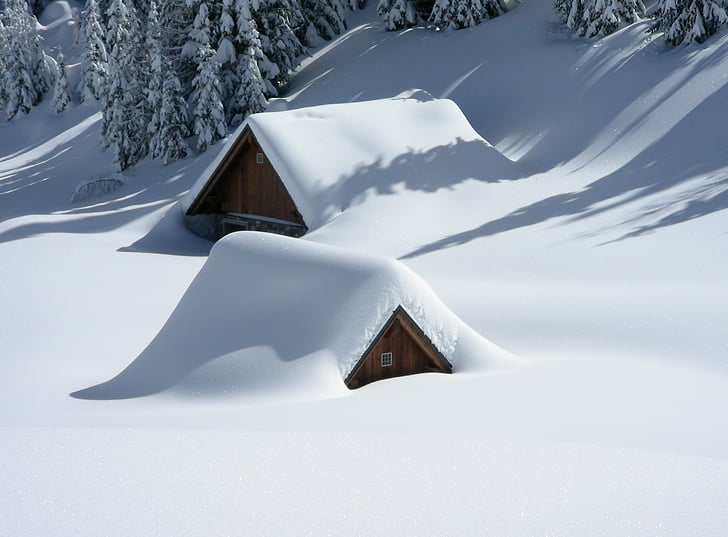 two brown huts covered in snow