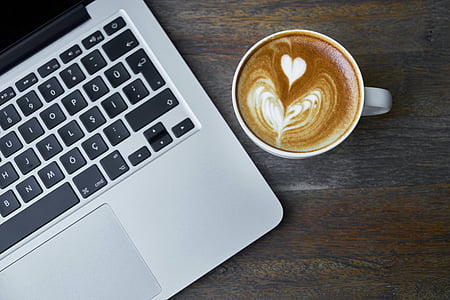 MacBook Pro near cup of cappuccino coffee