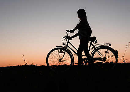 photography of silhoutte of person beside commuter bike