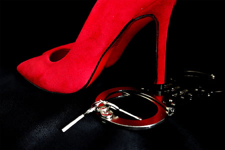 photo of gray handcuff and unpaired red pointed-toe stiletto