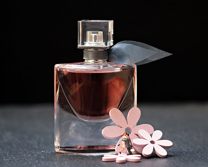 fragrance bottle beside three pink petaled flowers