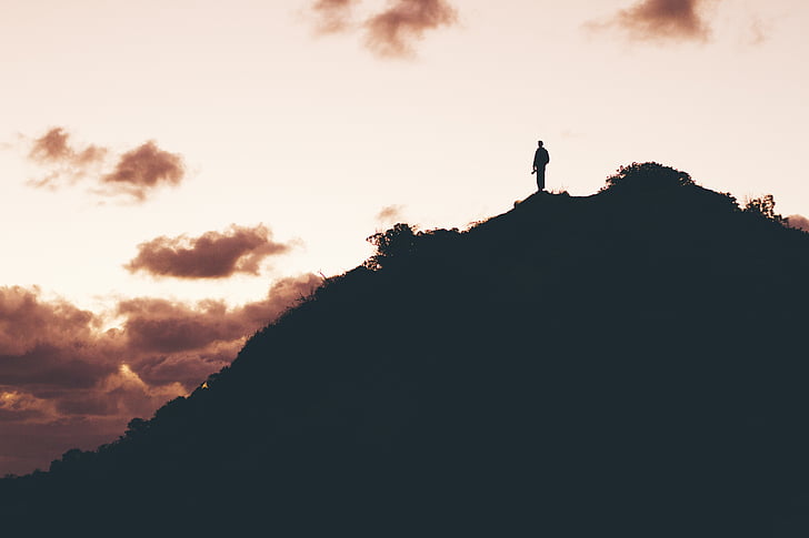 silhouette photo of man on top of hill