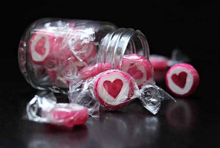 person taking photo of white-and-pink candies with jar