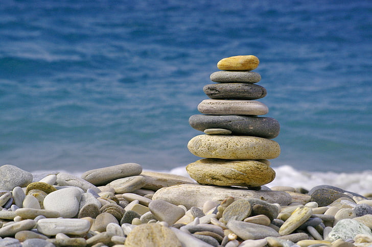 gray and black stack of stones near the ocean at daytime