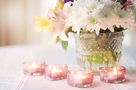 white petaled flowers and four pink tealight candles