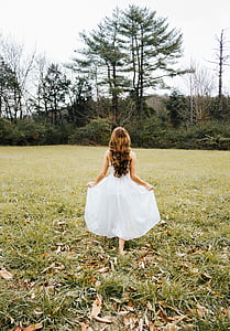 photo of woman in white dress standing on grass