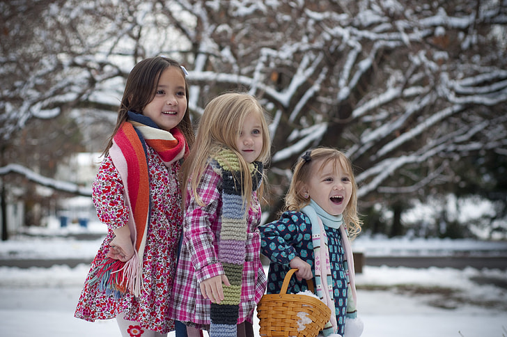 three girls wearing coat during snow time
