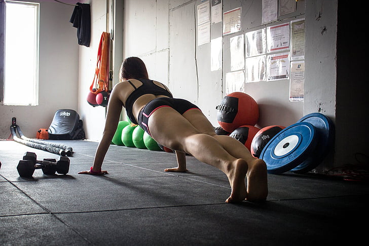 woman planking beside weight plates