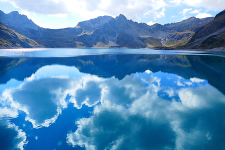 clear blue water reflecting the sky between mountain ranges during day time