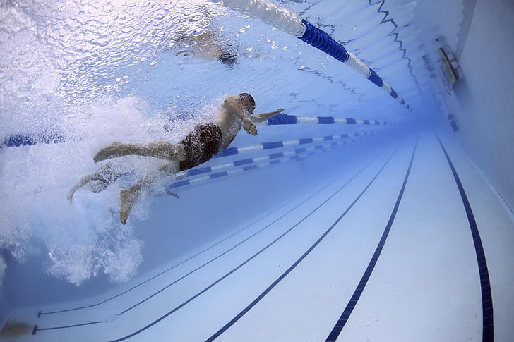 man swimming under pool