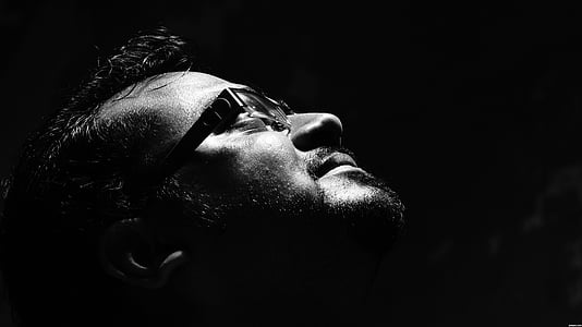 grayscale photo of man wearing eyeglasses looking up