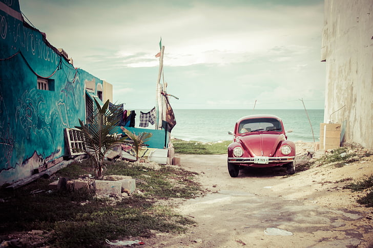 red Volkswagen Beetle in the beach during daytime