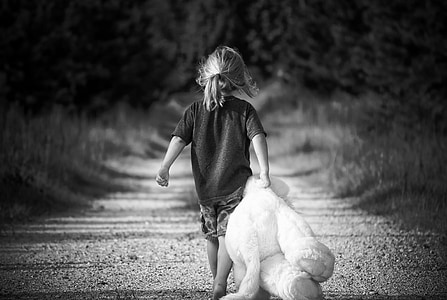 grayscale photo of girl wearing t-shirt holding teddy bear
