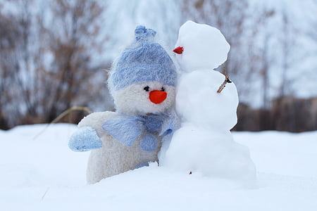 snowman plush toy beside snowman at daytime