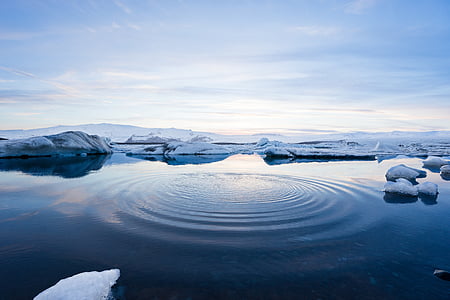 body of water surrounded by ice during daytime
