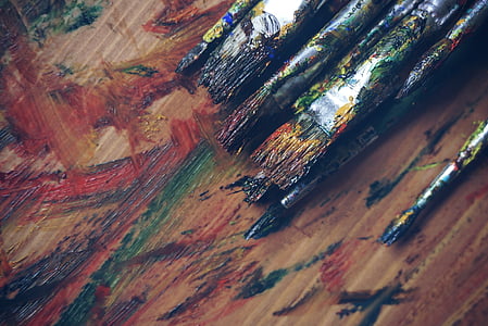 assorted-color paint brush on brown wooden table