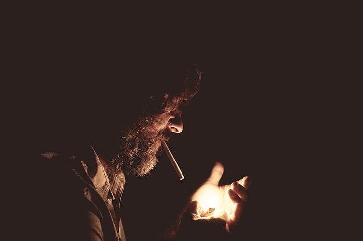 man holding lighter inside dark room