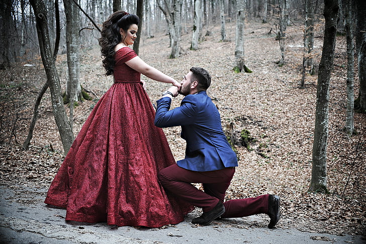 man wears blue suit and women's red dress in the forest