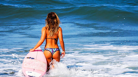 woman wears bikini holds surfboard at daytime in sea