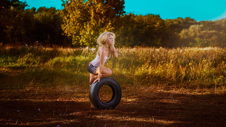 woman in white tank top holding vehicle tire