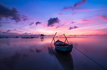 canoe on body of water with blue and pink sky