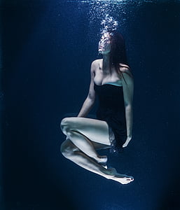 woman in black tube dress floating underwater