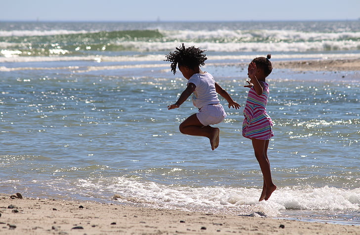 two child hopping near seashore