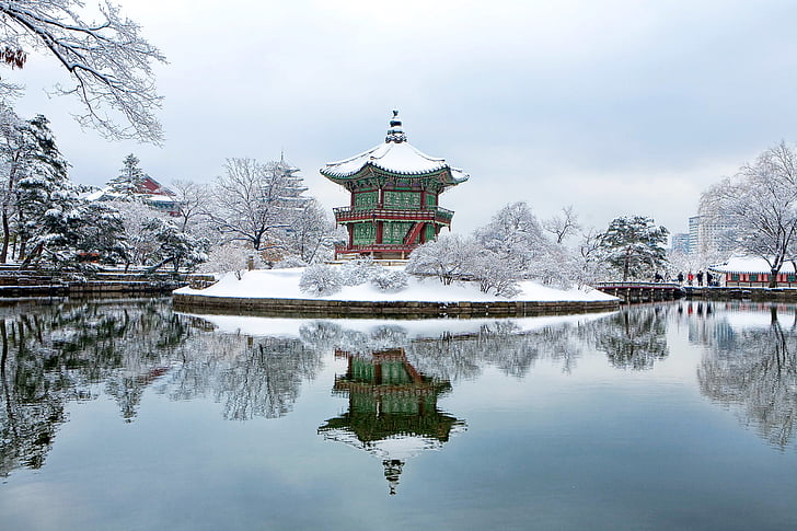 green and red snow covered temple in middle body of water