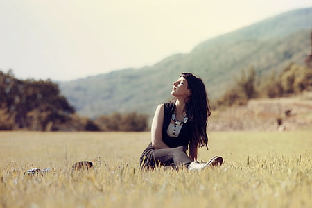 woman in white and black top sitting on grass field photo