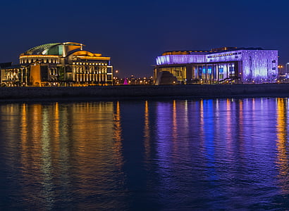 two lighted buildings near body of water during nighttime