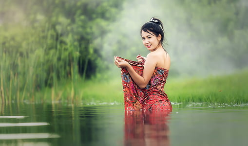 woman wearing red and multicolored tube dress stand on body of water