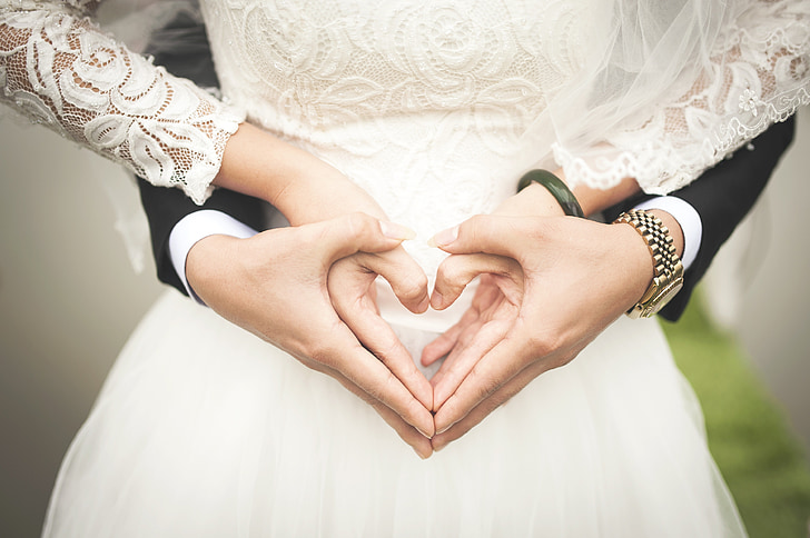 man and woman holding hands doing heart hand sign