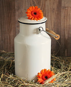 white ceramic jar with orange flower on top