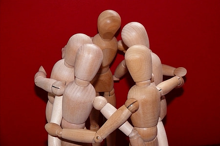 five brown wooden puppet hugging each other