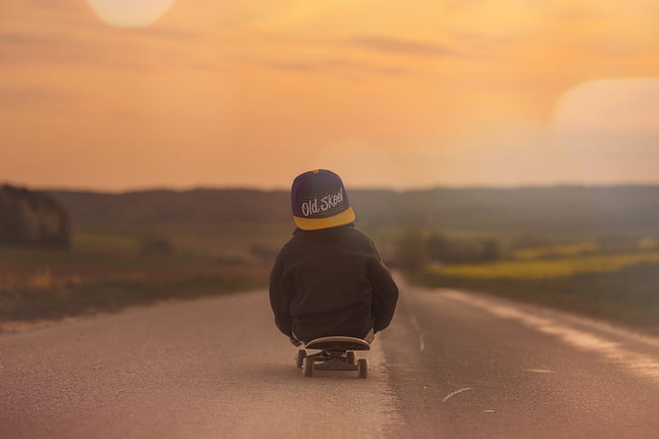 toddler on skateboard towards road during golden hour