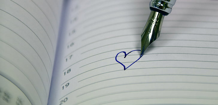 silver fountain pen drew a heart in white ruled paper