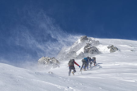group of people climbing mountain covered in snow at daytime