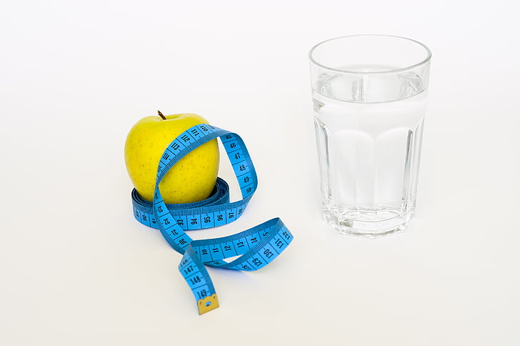 yellow fruit on tape measure near glass filled with water